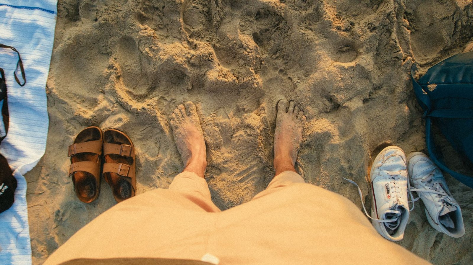 Pies descalzos junto a unas sandalias de verano