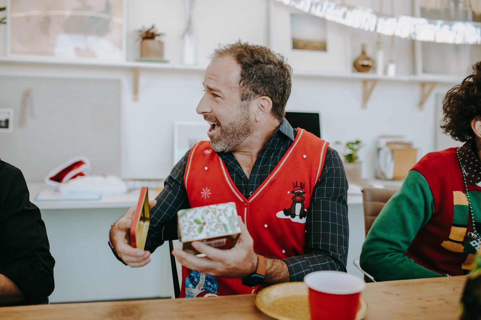 Un hombre abre un regalo envuelto sentado en el sofá