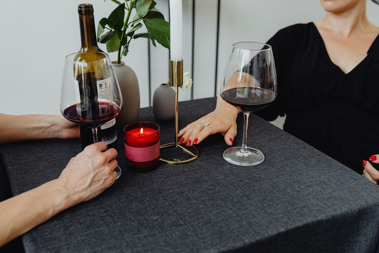 Mesa puesta para dos con velas y copas de vino en una cena en casa
