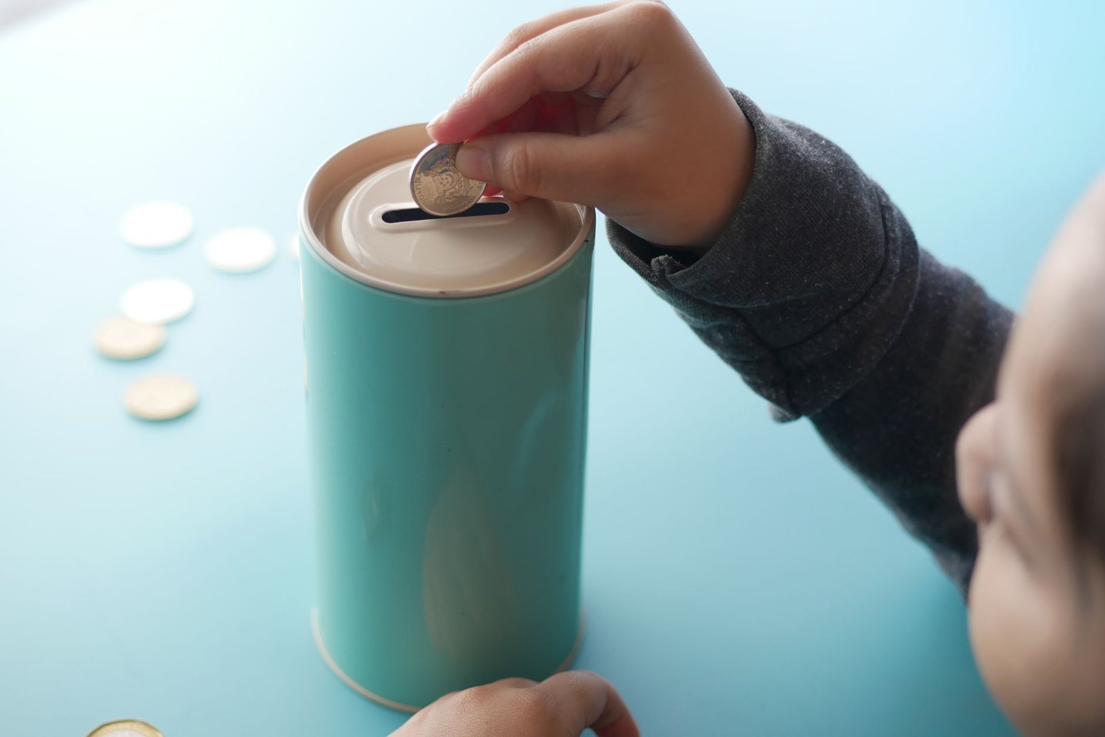 Niña metiendo monedas en una hucha sobre una mesa