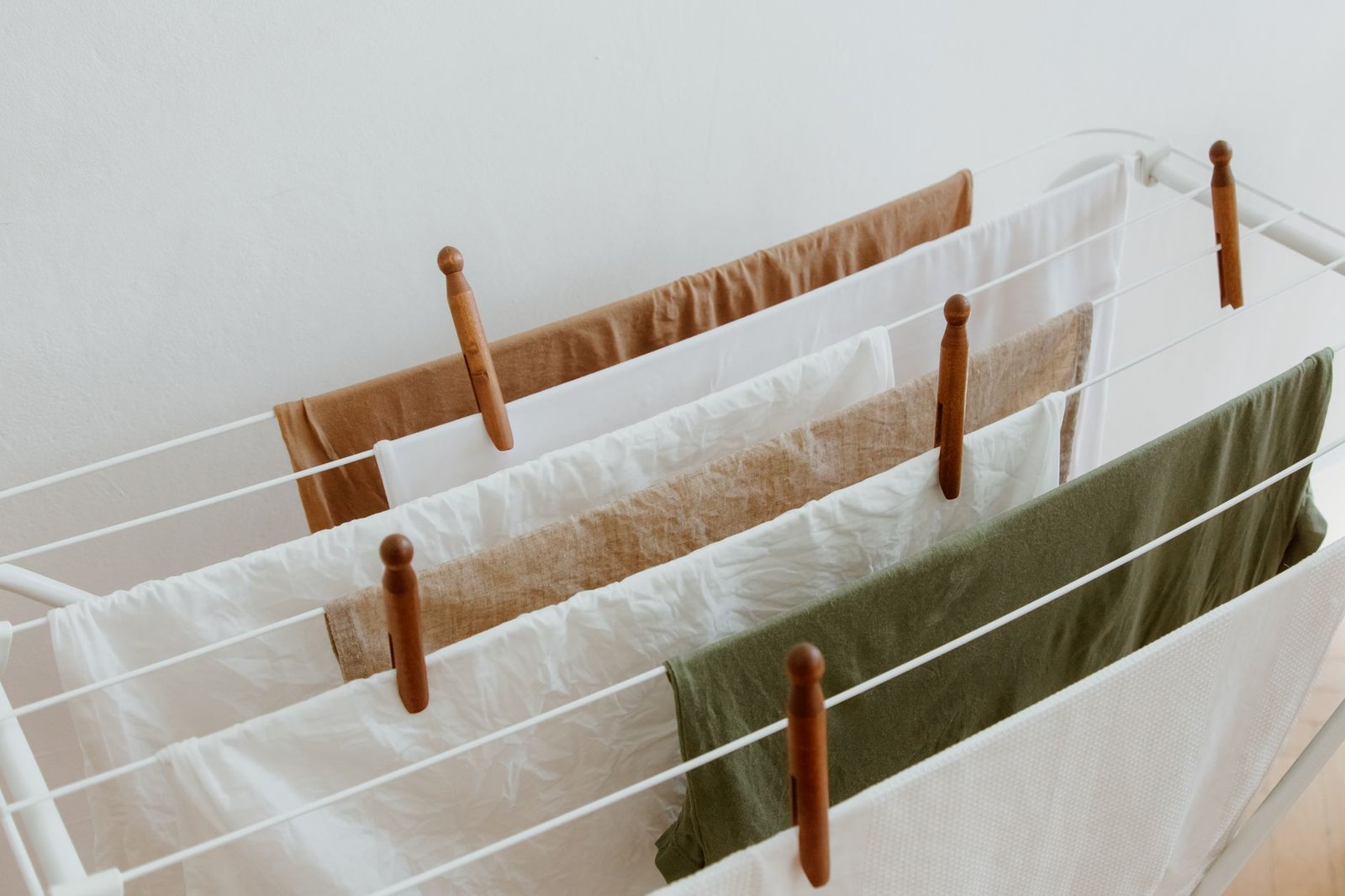 Tendedero con ropa colgada dentro de una habitación junto a una ventana