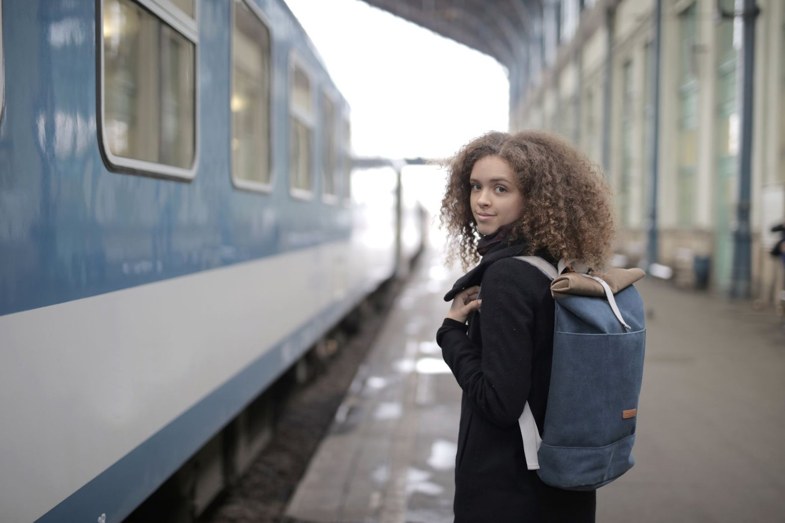 Mujer con maleta pequeña esperando en el andén de una estación de tren