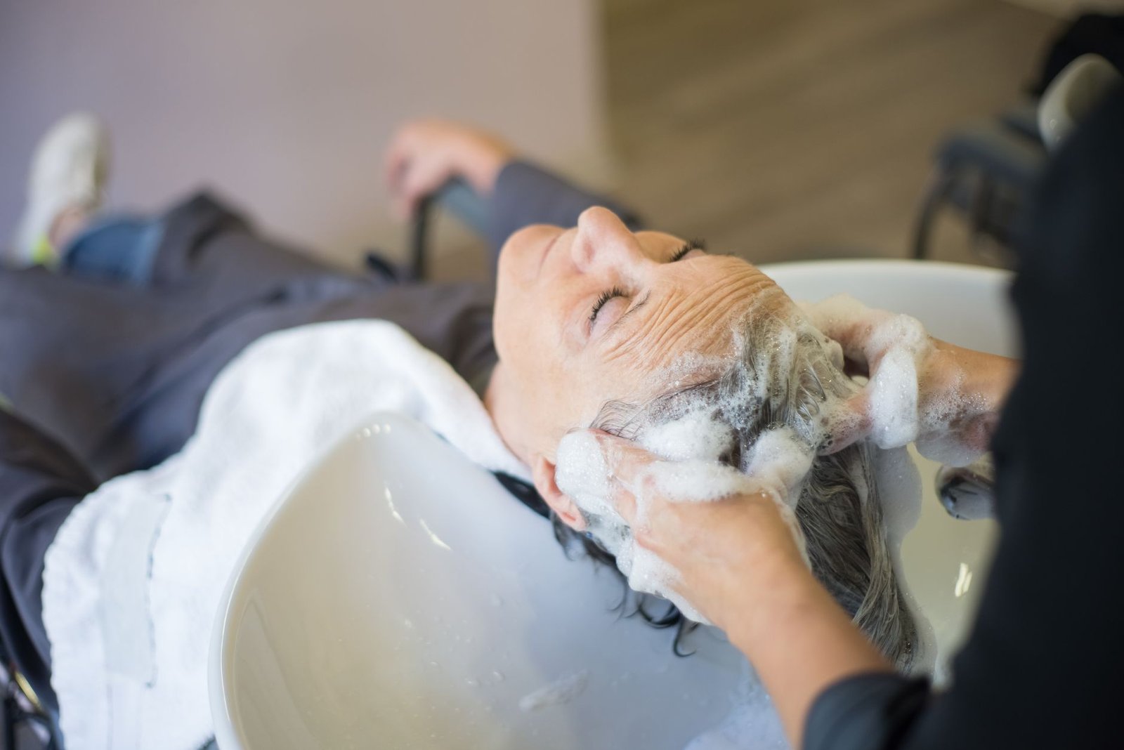 Mujer aplicando champú sobre el cuero cabelludo en la ducha